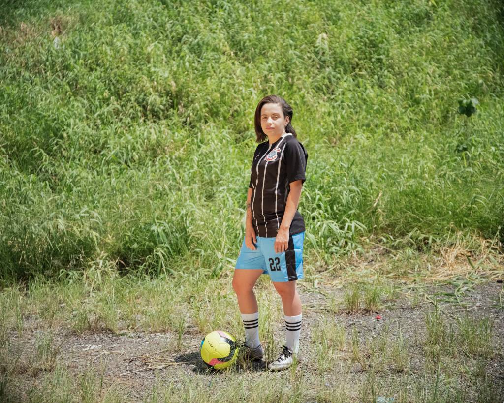 Foto de Kimberly posando com o pé na bola de futebol na grama