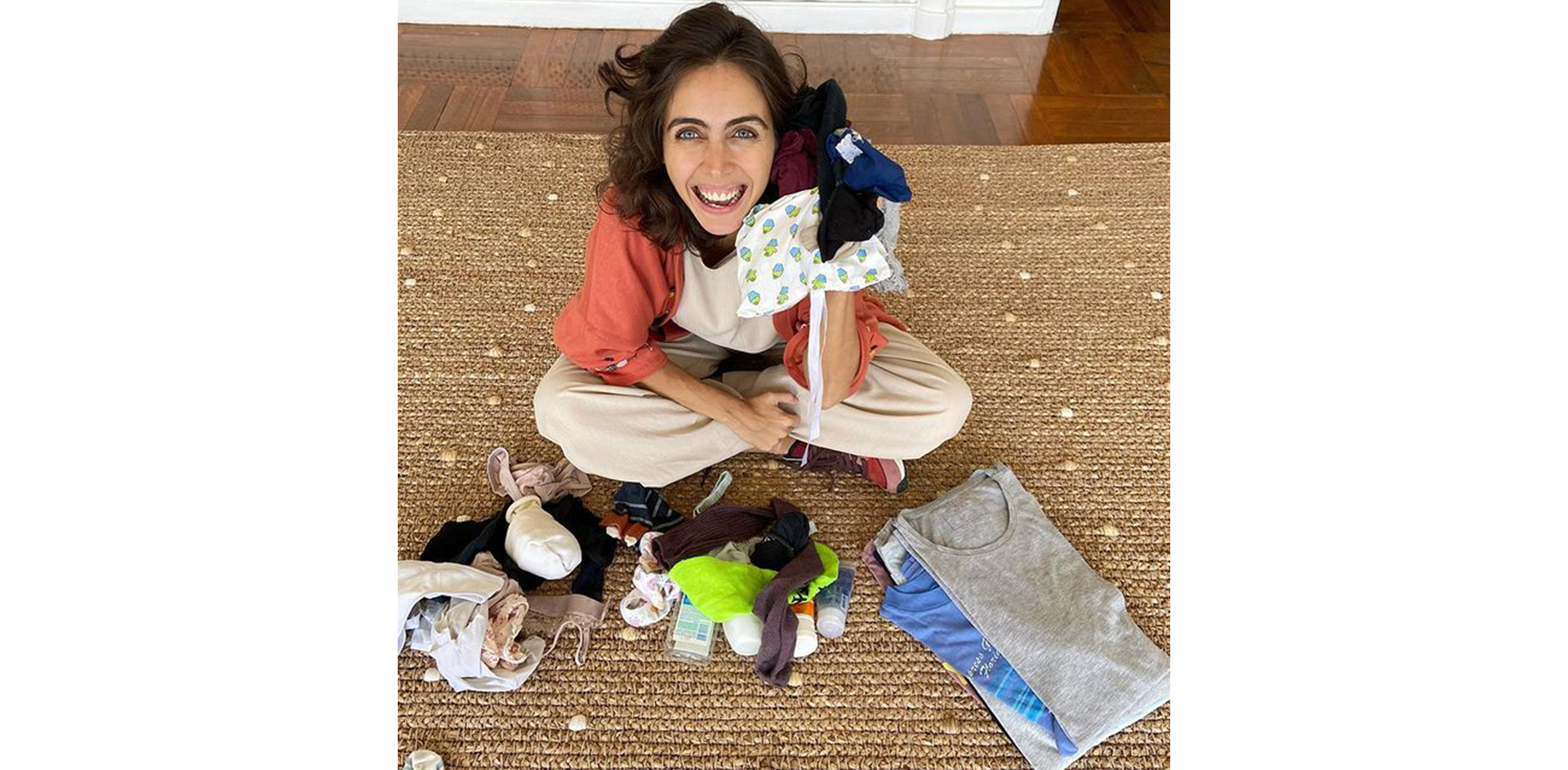 Giovanna Nader sentada no tapete com algumas roupas