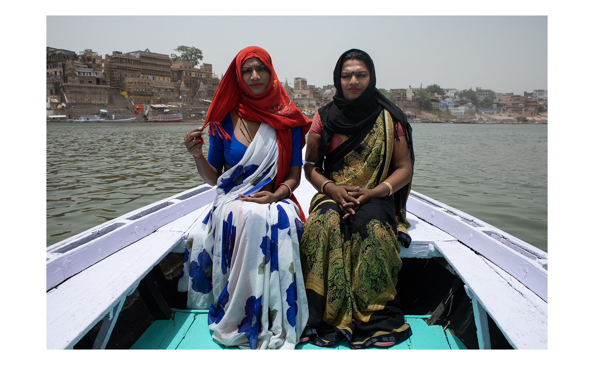 Rupaa e Muskan posam para retrato em um barco no rio Ganges, em Varanasi. Rupaa e Muskan são amigas e vivem na mesma comunidade de Hijras. Muskan frequentemente acompanha Rupaa quando elas precisam sair da comunidade, é comum as hijras circularem pela cidade em grupos por questões culturais e por segurança.