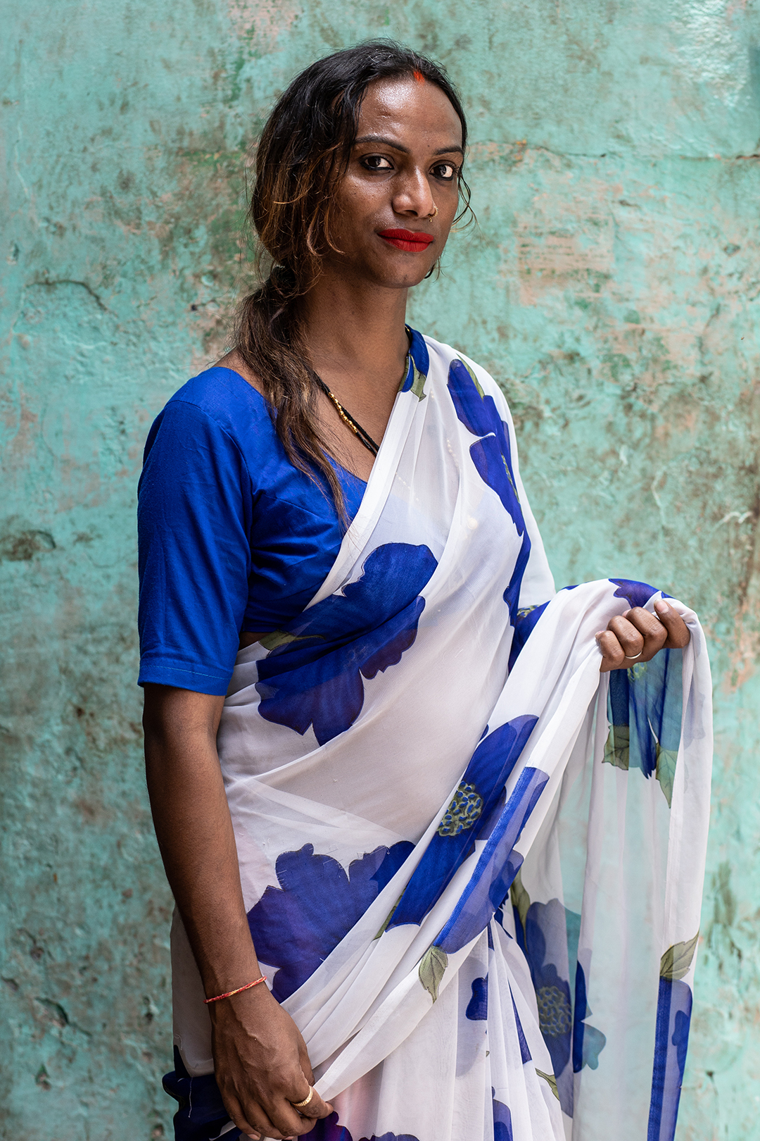 Rupaa posa para retrato na frente de uma casa em Varanasi, Índia. Durante umaconversa Rupaa relaciona sua identidade de gênero à decisões divinas.