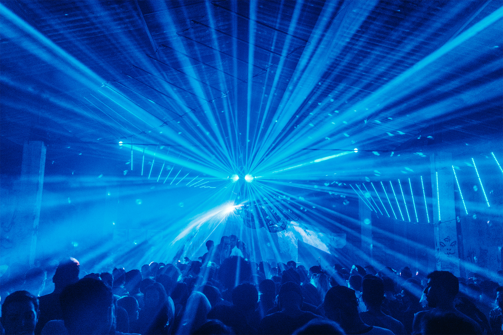 foto de feixos luzes azuis em uma festa e pessoas dançando